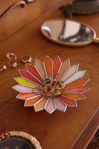 stained glass colorful flower ring holder on vintage vanity with mirror reflection and hands, elegant jewelry tray