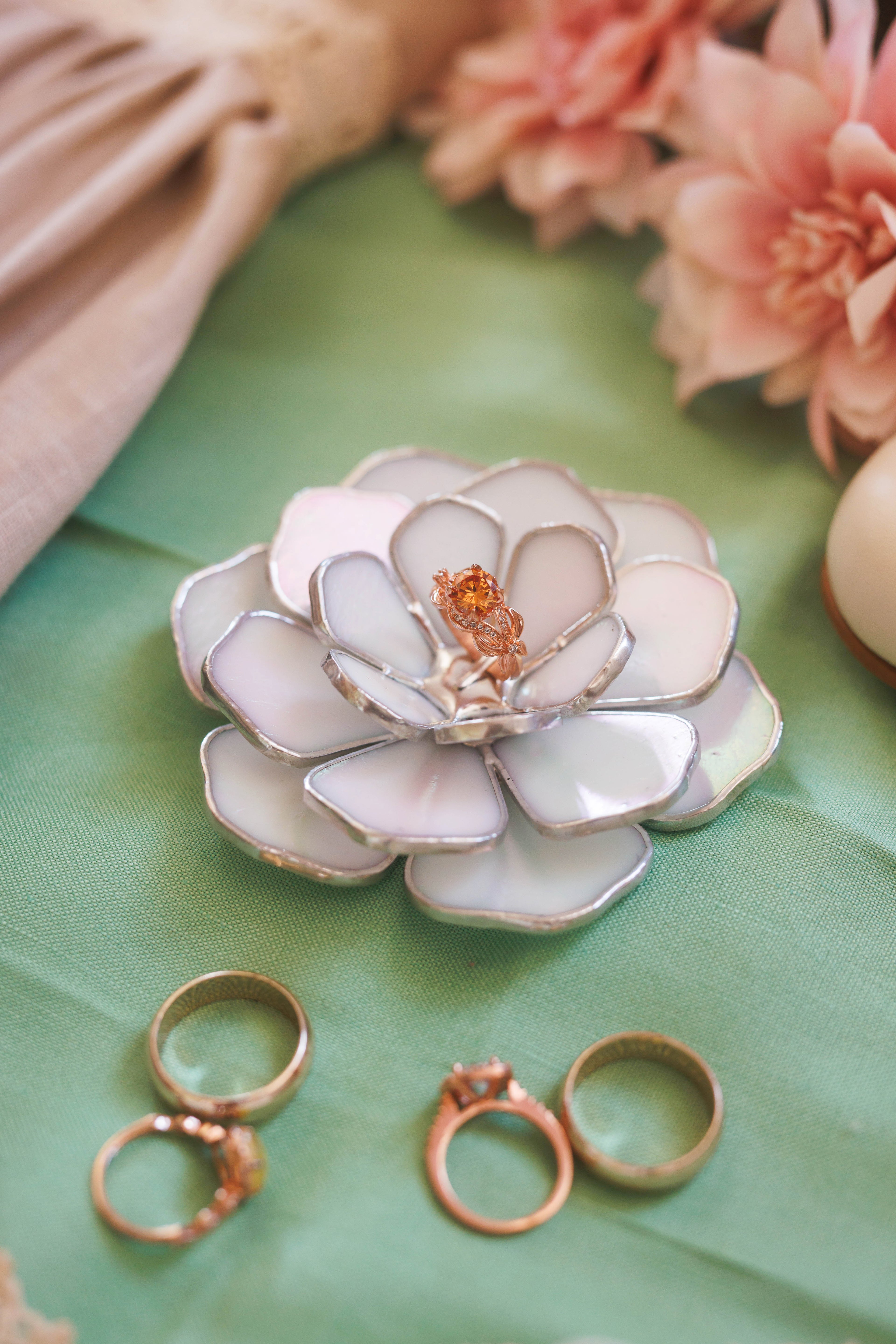 Stained glass floral ring holder with rings on a green fabric background