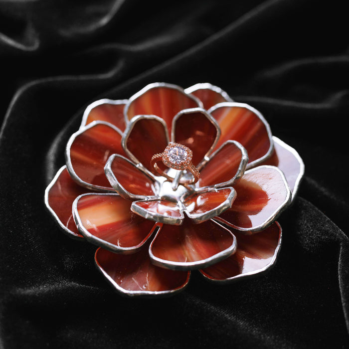 Stained glass floral ring dish with a ring on a black velvet background