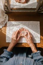 Grandma holding a decorative flower-shaped jewelry dishon a wooden table with a mirror in the background.