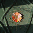 Colorful sunburst stained glasss jewelry tray on a green fabric background